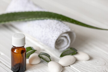Spa composition with a jar of natural oil and aloe leaves with a towel.
