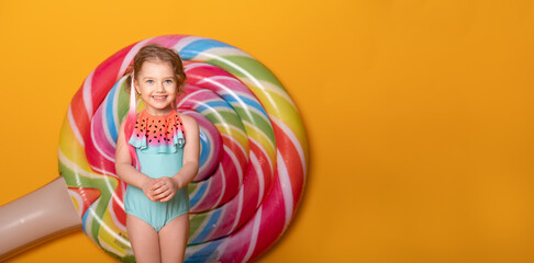 Funny little girl in swimming suit smiling having fun on yellow background. banner