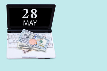 Laptop with the date of 28 may and cryptocurrency Bitcoin, dollars on a blue background. Buy or sell cryptocurrency. Stock market concept.