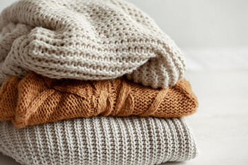 Obraz na płótnie Canvas A stack of warm knitted sweathers on blurred background.