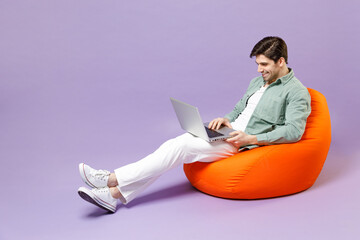 Full length fun happy man 20s wearing casual mint shirt white t-shirt sitting in orange bean bag...