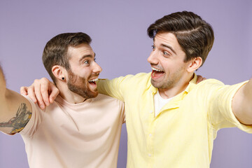 Fototapeta premium Close up young overjoyed men friends together in casual tshirt do selfie shot on mobile phone post photo on social network look each other hug isolated on purple background People lifestyle concept
