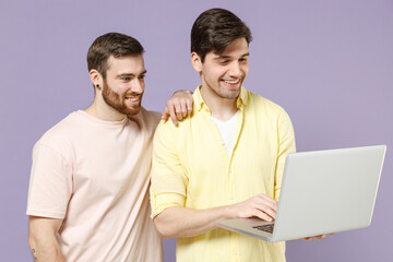 Young smiling happy men friends together wearing casual t-shirt tattoo translate fun hold laptop pc...
