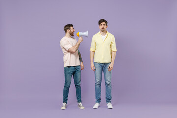 Fototapeta premium Full length shocked confused disappointed young men friends together in t-shirt scream hot news in megaphone fooling around isolated on purple background studio. People lifestyle friendship concept