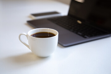 Close up of a coffee cup in the workplace near a laptop.