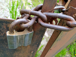 Lock on a thick chain close-up covered with rust