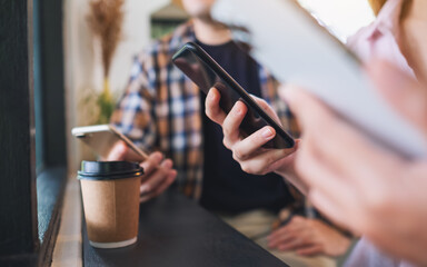 Group of young people holding and using their mobile phones while sitting together