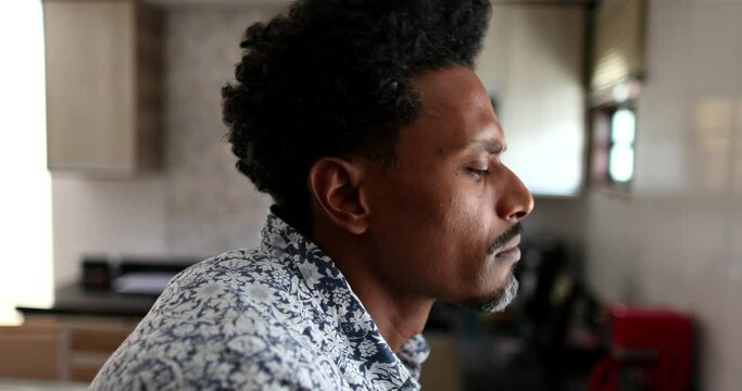 Frustrated Black African man standing in kitchen at home concerned about future