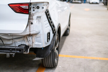Car crashed at the rear body close up, a modern white SUV car was damaged at the back and repairing in garage.