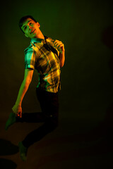 The guy in the checkered shirt dances, illuminated by orange and green light