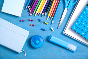 Calculator, pencils, note, eraser scissors, marker, sticky notes on the blue background.