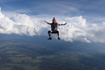 Fototapeta na wymiar Skydiving. A guy is falling in sit position. Amazing clouds are in the background.