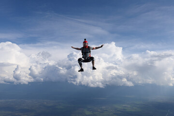 Naklejka na ściany i meble Skydiving. A guy is falling in sit position. Amazing clouds are in the background.