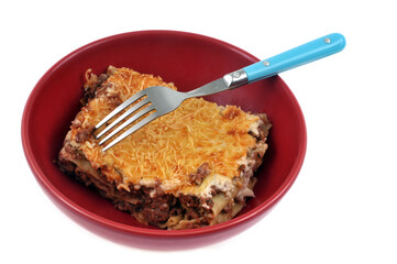 Assiette de lasagnes à la viande de boeuf servies dans une assiette avec une fourchette en gros plan sur fond blanc