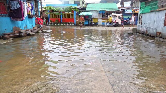 Monsoon season Philippines kids playing in the slums flooded streets