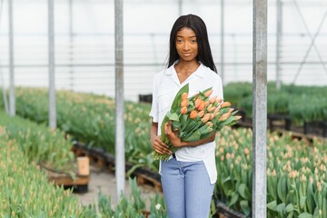 close up of african american woman holding flowers in greenhouse