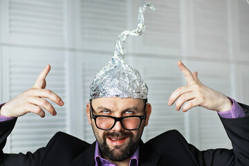 Bearded funny man in a cap of aluminum foil. Concept art phobias.Conspiracy theory. Conspiracy....