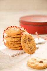 Choc chip cookies tied in a stack with red biscuit tin