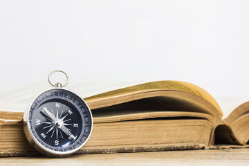 An old compass with book on table.