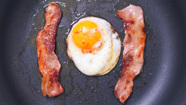 fried bacon with eggs in a pan, top view. tasty breakfast