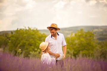 Father and daughter walking trough lavender field.