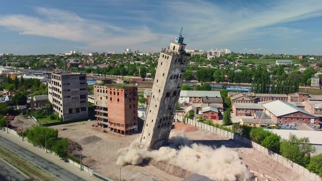 Building demolition by explosion. Controlled explosion abandoned old tower building on blue sky in the city. 