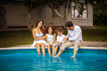 Fototapeta na wymiar Family sitting by the pool. Summer time in backyard.