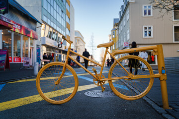 Fototapeta na wymiar The vibrant yellow bicycle mark the beginning of a cycling path in the busy city center of the Reykjavik, Iceland 