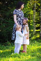 Fototapeta premium Young large family on a summer morning walk. Beautiful mother with children is playing in the park.