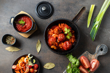 Roasted meatballs with tomato sauce and parsley in a frying pan on dark background.