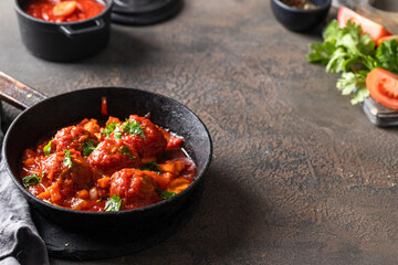 Frying pan with homemade Meatballs in tomato sauce with parsley  on concrete table.Copy space