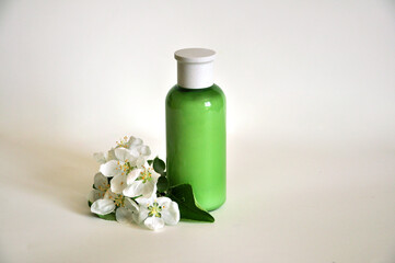 Green glass bottle with white flowers on a white background. Mockup