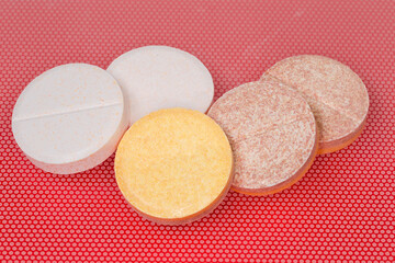 Effervescent tablets on red surface, close-up in selective focus