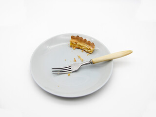 Leftovers from a piece of baked pie on a gray plate and a fork. Food stubs.