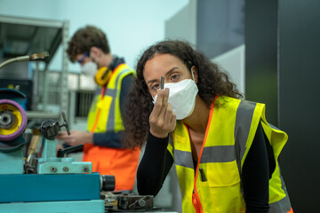 Engineer woman wearing protection face mask working and checking machine in the factory.