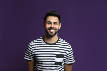 Fototapeta premium Young man laughing on purple background. Funny joke