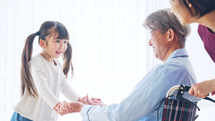 Obraz premium 車椅子のシニア男性とエッセンシャルワーカー お見舞いに来た女の子 介護イメージ