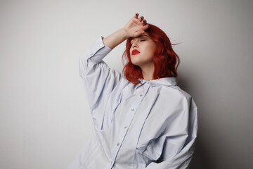 Young woman with red hair posing in the studio over grey background. 