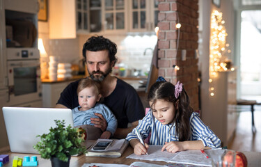 Father with small daughters in kitchen, distance learning, home office and schooling concept.