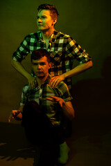 Fototapeta na wymiar Two guys sitting on the floor in the studio. illuminated by yellow and green light