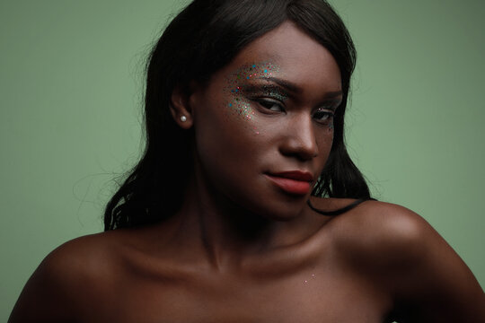 Close-up of young Black woman posing in the studio, with glittery make-up.