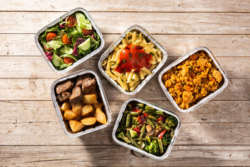 Take away healthy food in foil boxes on wooden table. Top view