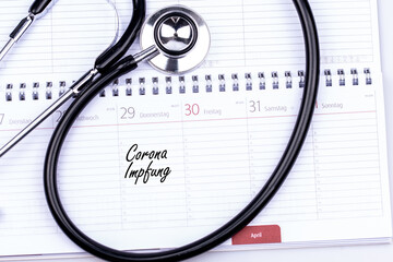 Terminkalender beim Hausarzt mit einem Stethoskop und einem Eintrag Corona Impfung