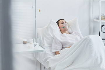 Obraz premium Senior woman in oxygen mask lying on bed in reanimation