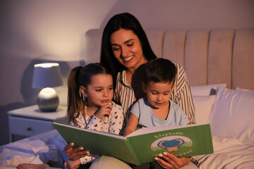 Mother reading bedtime story to her children at home - Powered by Adobe