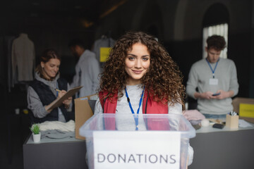 Woman volunteer working in community charity donation center, looking at camera.