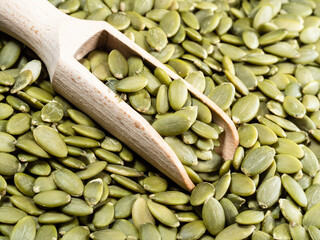 wooden scoop on heap of peeled pumpkin seeds