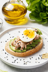 Avocado, canned tuna and boiled egg toast on white stone table background. Healthy food, avocado open sandwich for breakfast or lunch. Close up