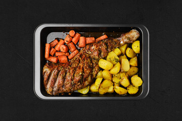 Overhead view of baked lamb shoulder with potato and carrot in oven-tray
