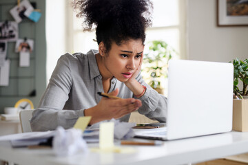 Frustrated young woman with laptop indoors at home, home office concept.